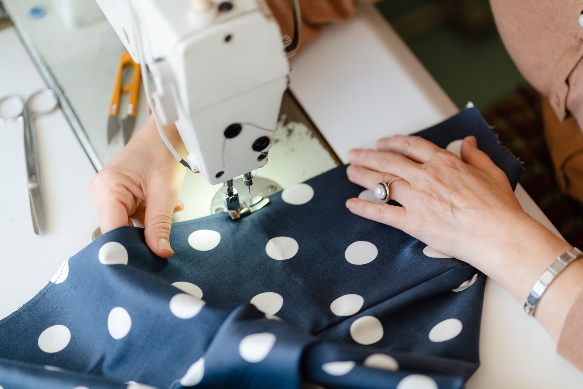 Close up of sewing machine needle and seamstress's hands sewing clothes